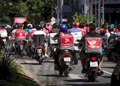 Trabajadores precarizados de Rosario realizan repartos en moto en medio del tránsito urbano.
